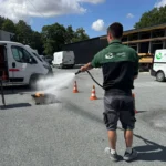 Un membre de l'équipe de l'entreprise Jeudy s'entraîne avec un extincteur